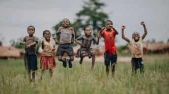 Des enfants sautent et rient dans un champ, incarnant la joie, l’espoir et la liberté que chaque enfant mérite en cette Journée dédiée à l’enfance.